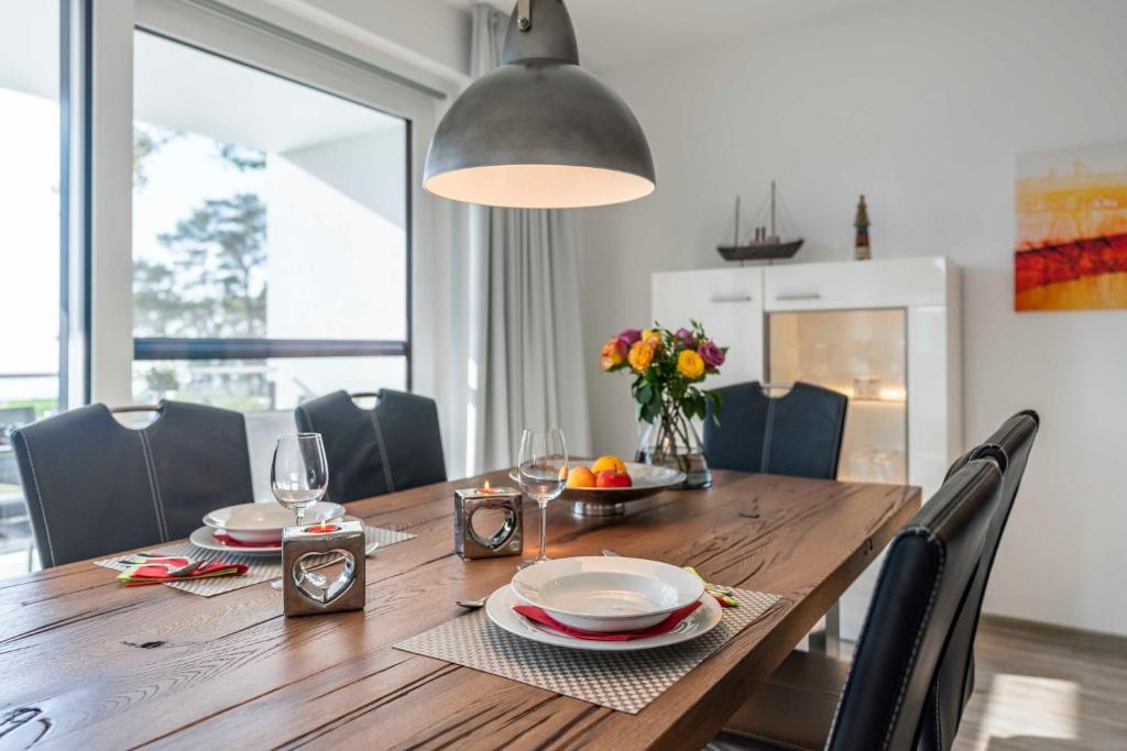 een eettafel met stoelen en een groot raam bij Appartement Schilfperle - Oase am Haff in Garz