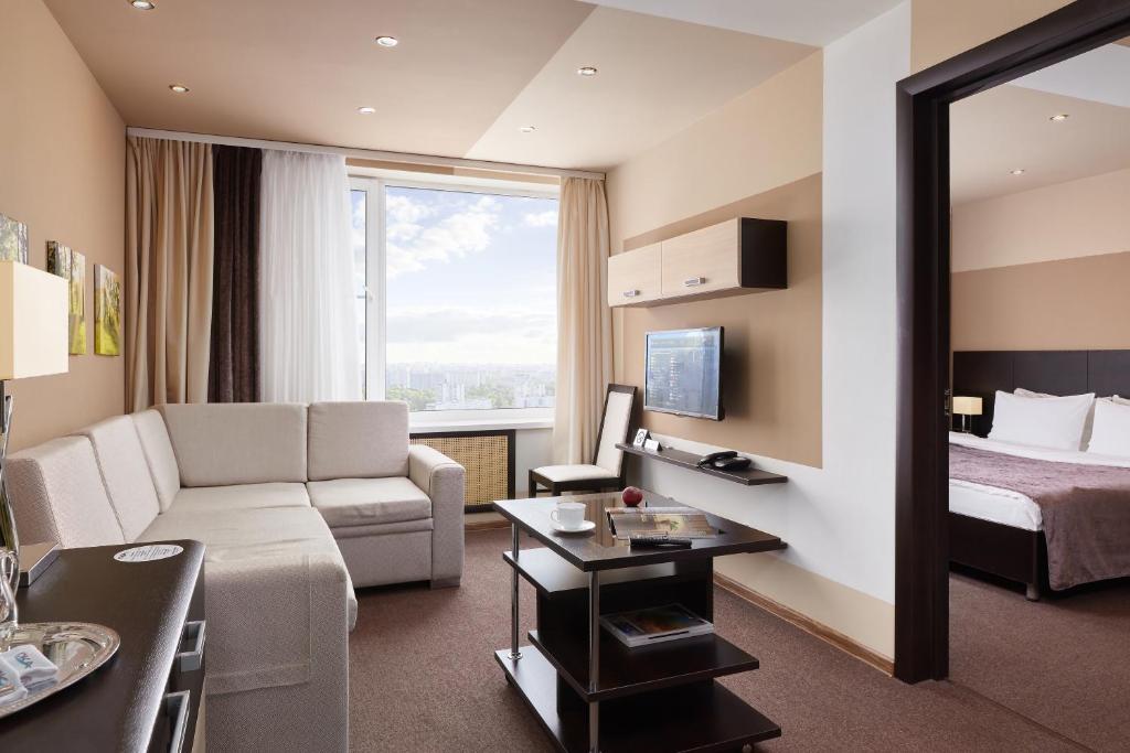 a hotel room with a couch and a bed and a mirror at Grand Hotel Oka Business in Nizhny Novgorod