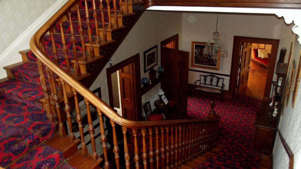 a wooden staircase in a living room with a stair case at Gardenvale Manor House B&B in Stranocum