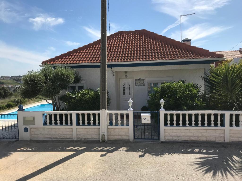 uma casa branca com uma cerca e uma piscina em Vivenda da bela vista em Costa da Caparica