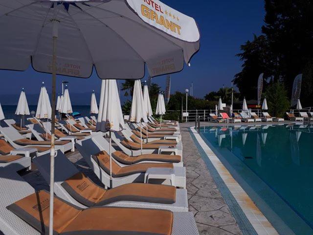 eine Reihe von Stühlen und Sonnenschirmen neben einem Pool in der Unterkunft Hotel Granit in Ohrid