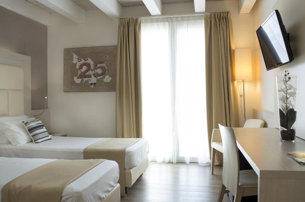 a hotel room with two beds and a desk and a television at Hotel Alexander in Mestre