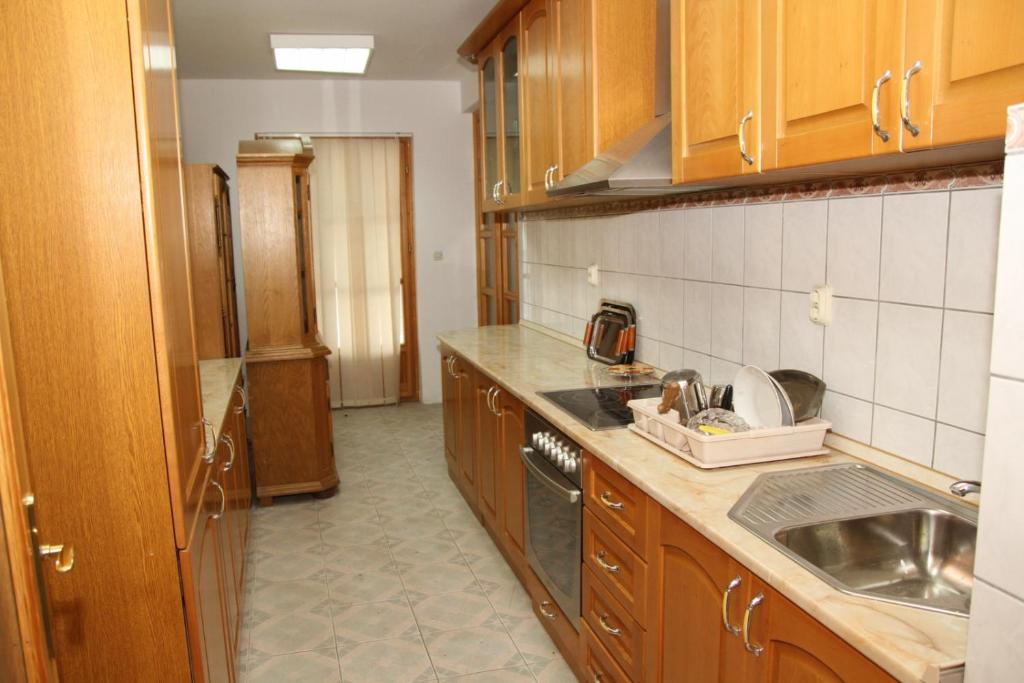 een keuken met houten kasten, een wastafel en een aanrecht bij Apartman Goražde in Goražde
