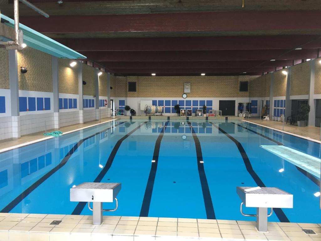 a large indoor swimming pool with blue water at Idrætscenter Jammerbugt in Fjerritslev