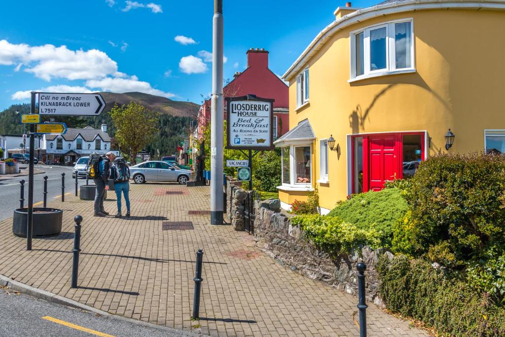 a person walking down a sidewalk next to a street at Liosderrig House B&B in Glenbeigh