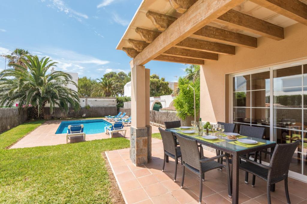 a patio with a table and chairs and a pool at Villa Laurax in Son Carrio