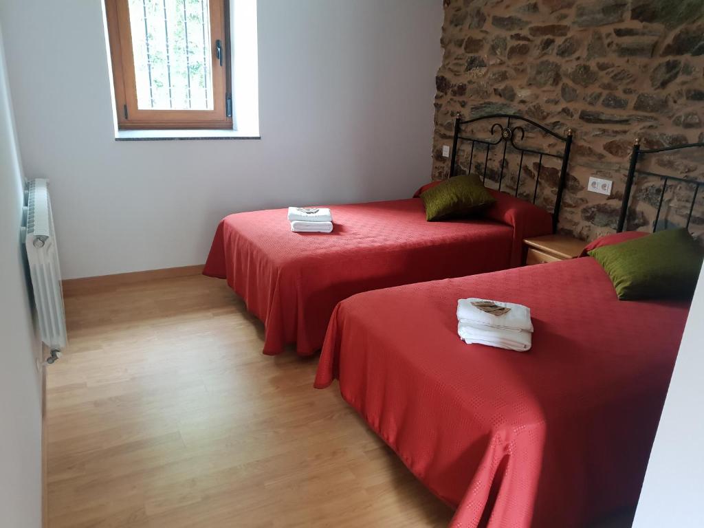 a room with two beds with red sheets and a window at Casa da Ponte in Ferreira