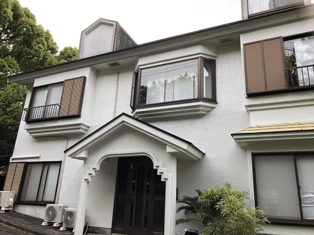 une maison blanche avec des fenêtres noires et une porte dans l'établissement Deer Head, à Itō