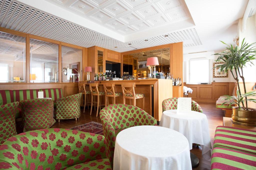 a restaurant with tables and chairs and a bar at Greif Hotel Maria Theresia in Trieste