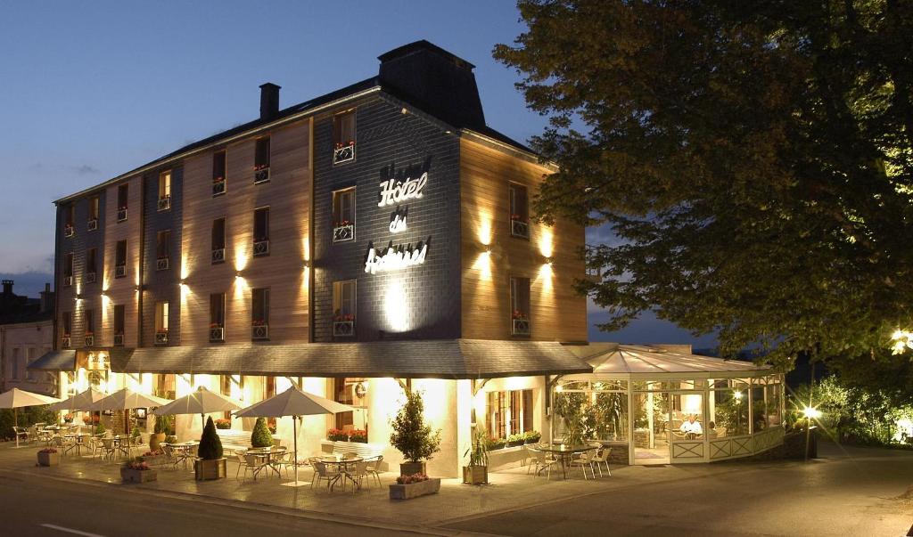 un edificio con tavoli e ombrelloni di fronte ad esso di Hotel des Ardennes a Corbion