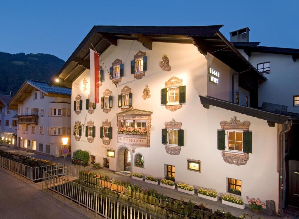 un edificio blanco con persianas y ventanas verdes en Eggerwirt Kitzbühel, Hotel & Restaurant en Kitzbühel