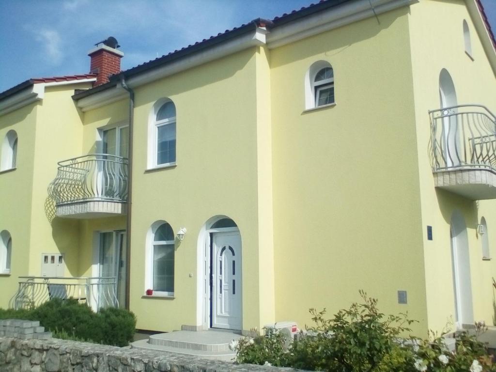 a large yellow house with balconies on it at Ana Rooms in Krk