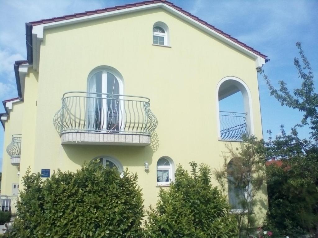 a large white house with a balcony at Ana Rooms in Krk