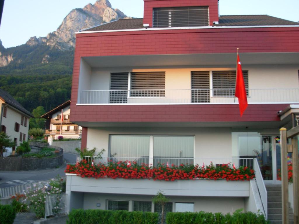 a building with a red flag on a balcony with flowers at Studio Mythen in Schwyz