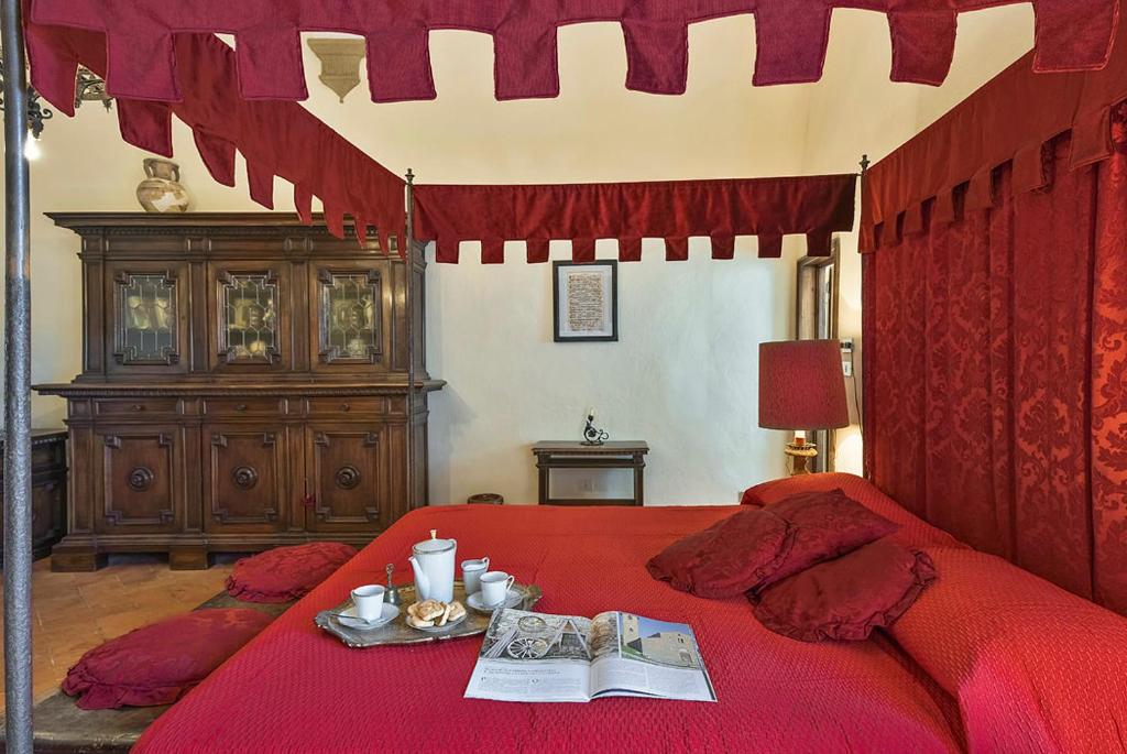 1 dormitorio con cama roja y edredón rojo en Medieval Palazzo Becci, en San Gimignano