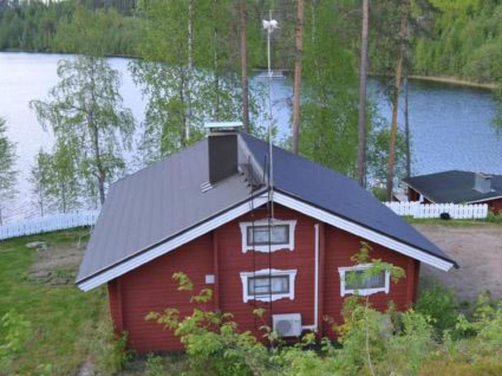 a red barn with a black roof next to a lake at Holiday Home Hirviharju by Interhome in Torsansalo