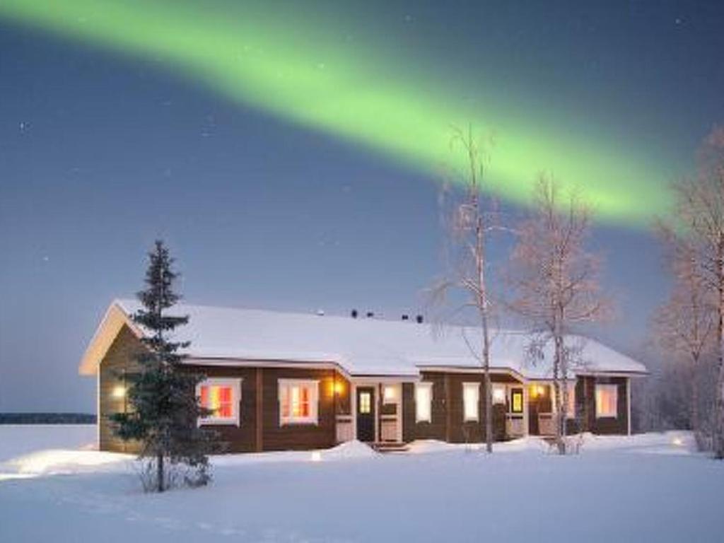 Ein Haus im Schnee mit einer Aurora darüber. in der Unterkunft Holiday Home Levin revontulitaivas 2 by Interhome in Köngäs
