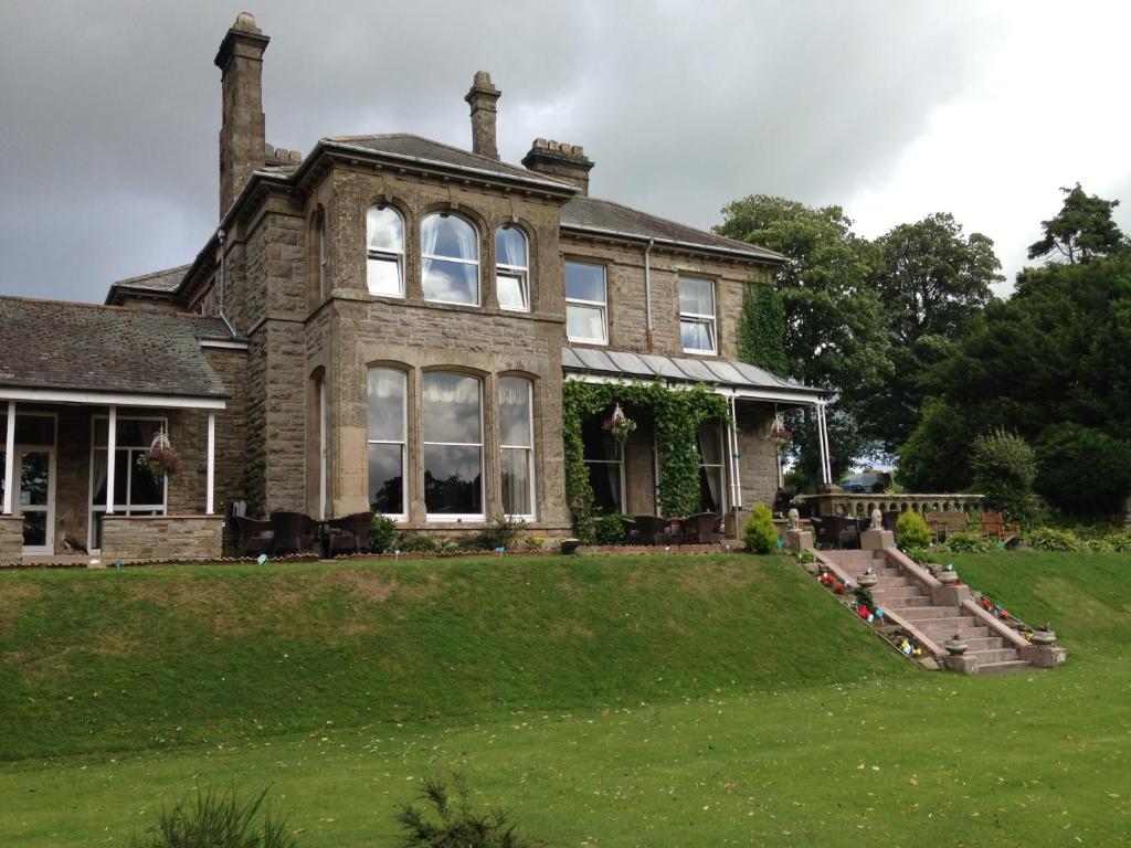 a large brick house with a lawn in front of it at Broughton Craggs Hotel in Cockermouth