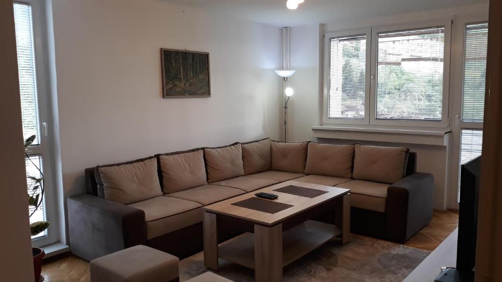 een woonkamer met een bruine bank en een tafel bij Apartment Ambrela 2 in Sarajevo