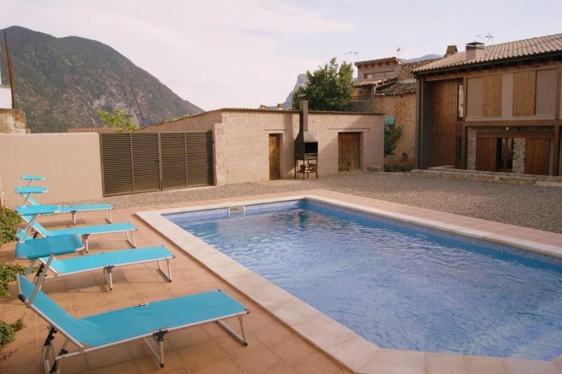 a swimming pool with blue chairs and a house at Cal Remolins in Coll de Nargó