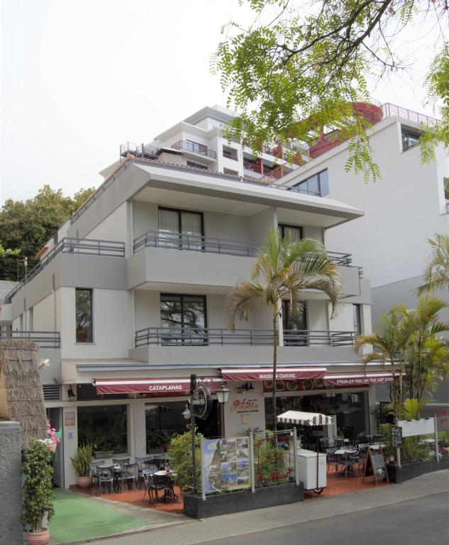 a white building with tables and chairs in front of it at Apartamentos Turísticos Vitoria by Petit Hotels in Funchal
