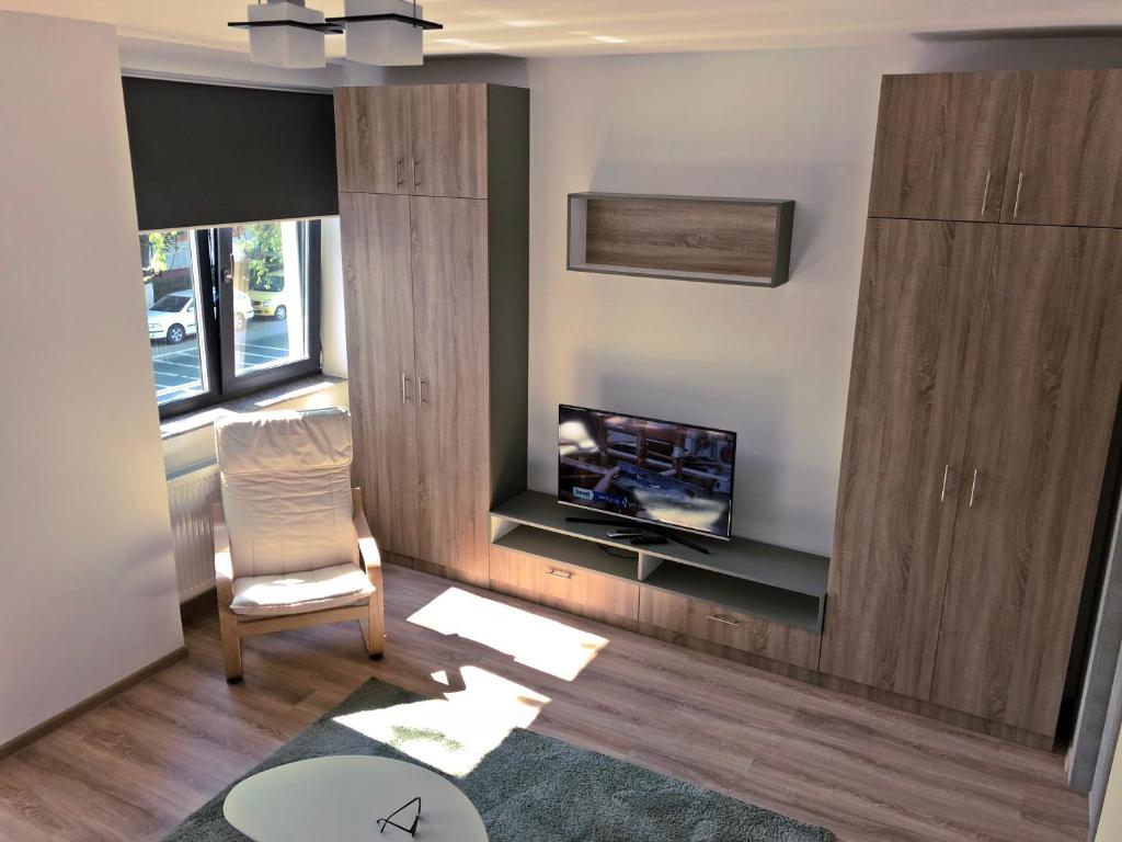 een woonkamer met een tv en een stoel bij Lira Holiday Apartments in Eforie Nord