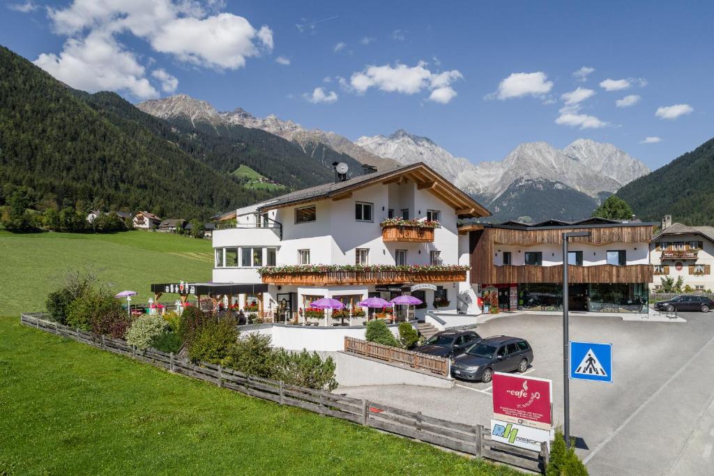 Un grand bâtiment blanc avec des montagnes en arrière-plan dans l'établissement Apartments Sankt Walburg, à Anterselva di Mezzo