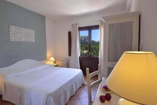 una camera con letto, lampada e finestra di Locanda Sant'Andrea Hotel & Relais a San Pantaleo
