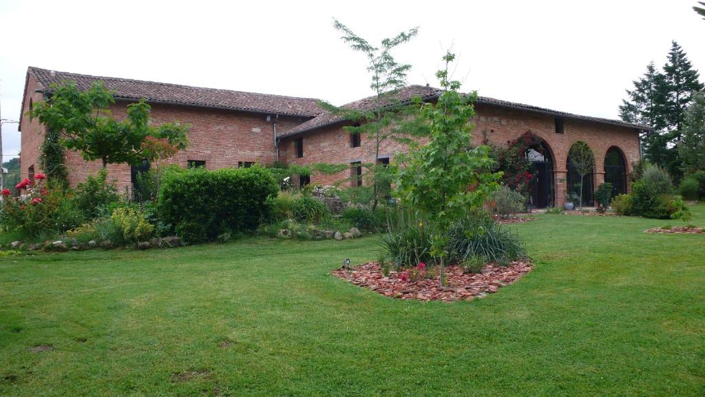 a large brick building with a garden in front of it at Domaine La Baronne in Buzet-sur-Tarn