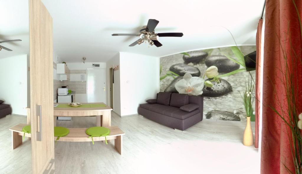 sala de estar con sofá y ventilador de techo en Orchidea apartman, en Harkány