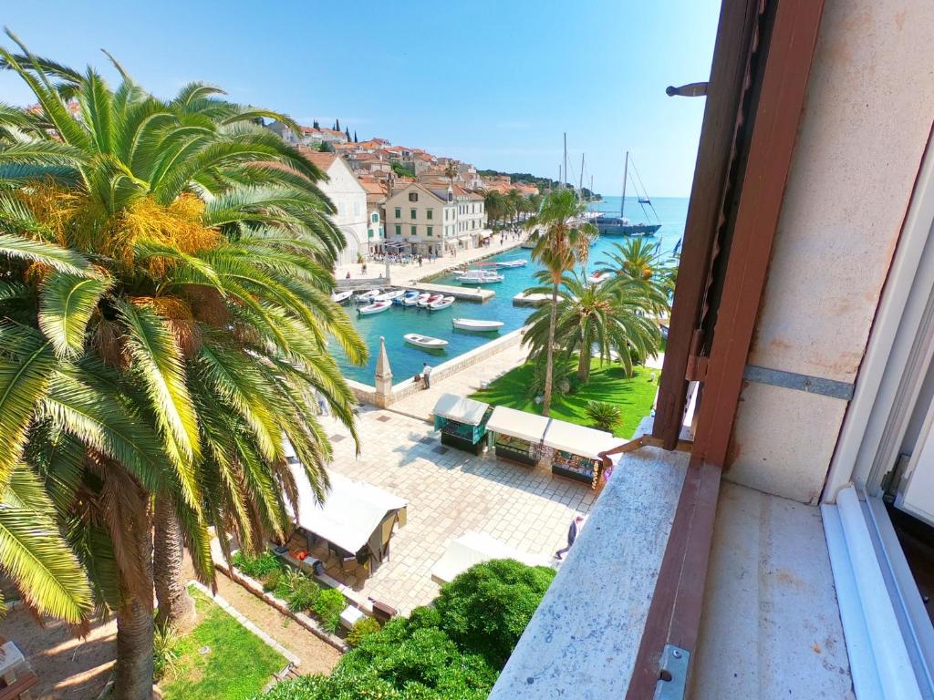 a view of a harbor from a balcony with a palm tree at Novak Bonaparte - Hvar city center in Hvar