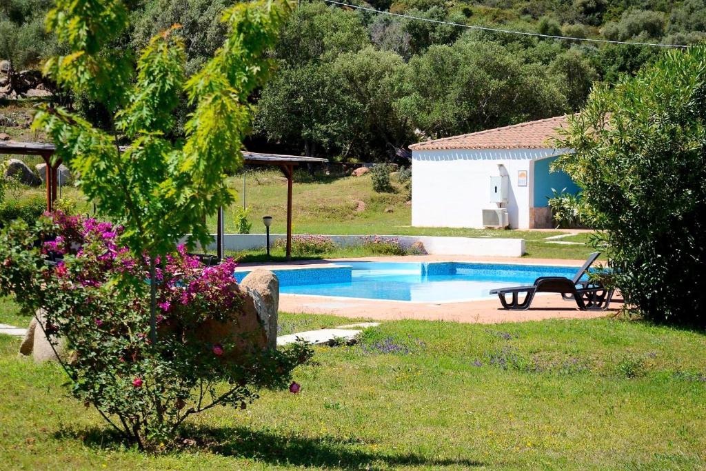 a swimming pool in a yard with a bench and flowers at Hotel Baia Cea in Bari Sardo