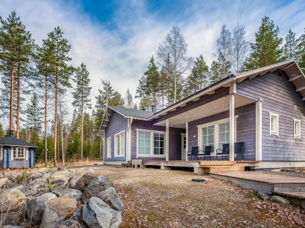 a house in the woods with rocks in front of it at Holiday Home Koholahti by Interhome in Jäniskylä