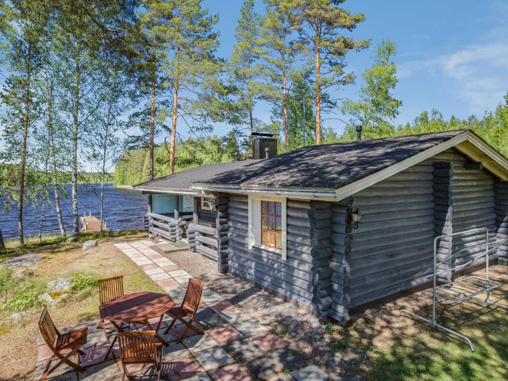 a cabin by the water with chairs and a patio at Holiday Home Aurinkoniemi by Interhome in Anttola