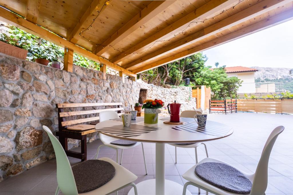 um pátio com uma mesa e cadeiras e uma parede de pedra em Apartments Ana Baska em Baska