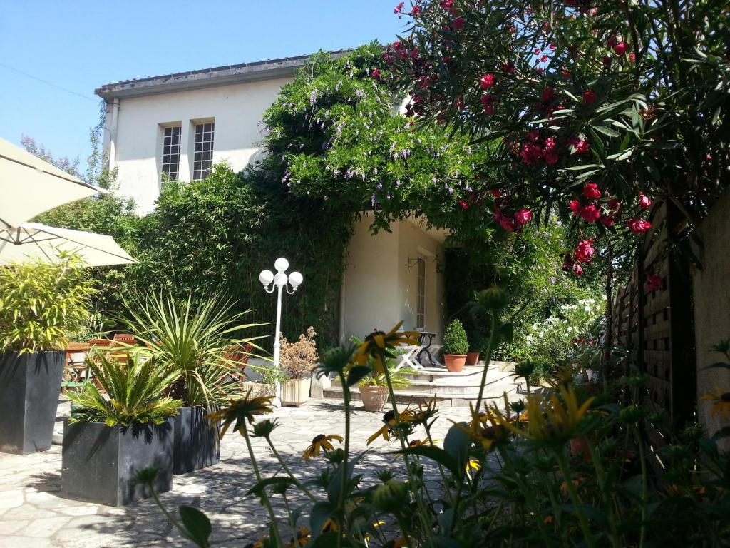 Ein Haus mit einem Haufen Pflanzen davor. in der Unterkunft Hôtel La Résidence in Villeneuve-sur-Lot