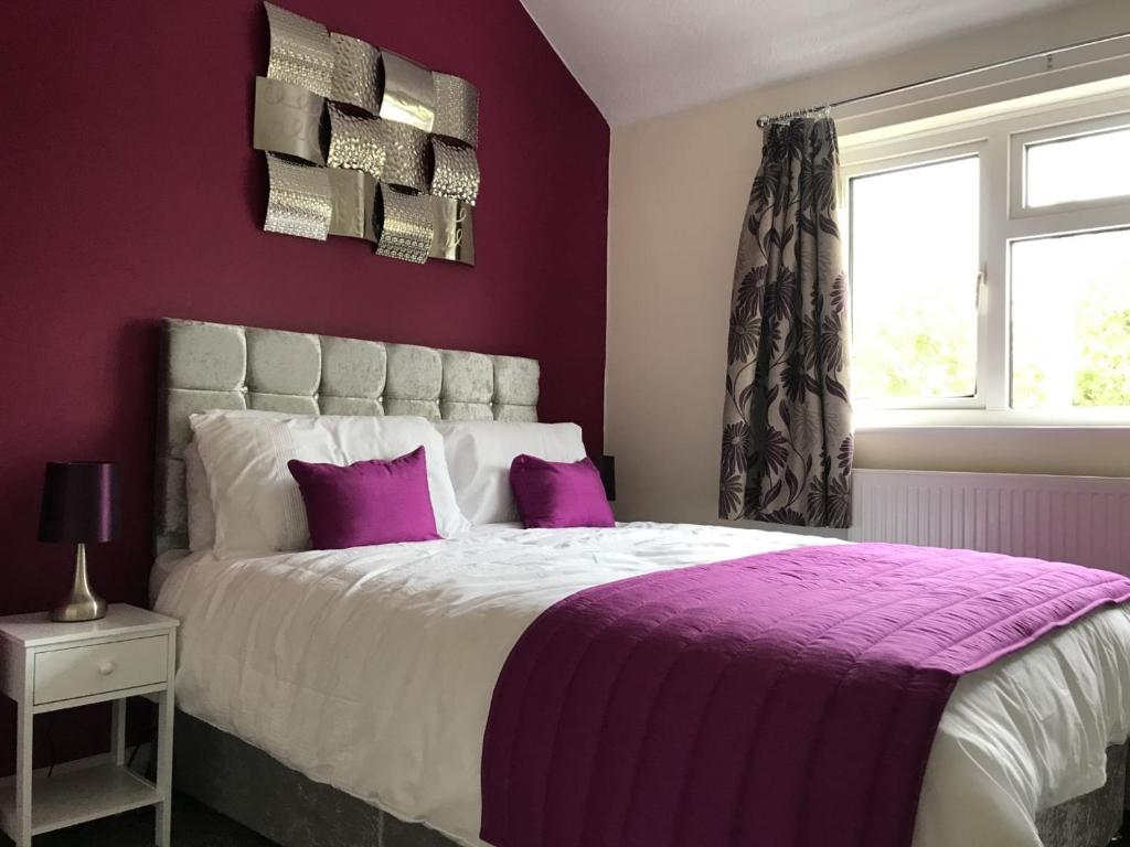 Dormitorio púrpura con cama grande con almohadas moradas en The Avenues en Chelmsford