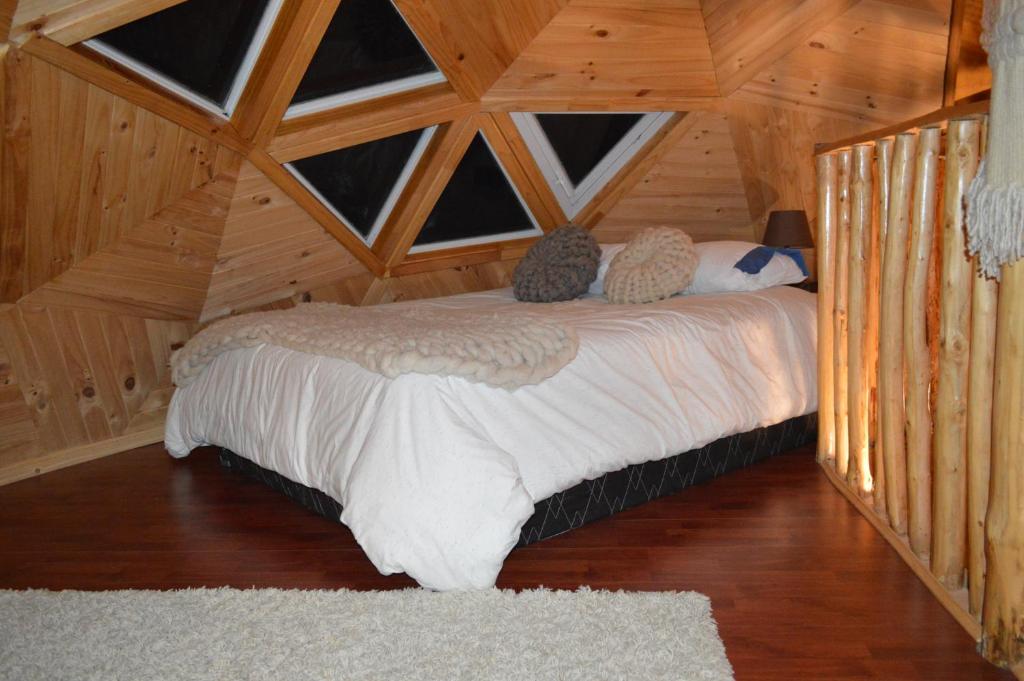 a bedroom with a bed with two cats sitting on it at domoschiloe in Ancud