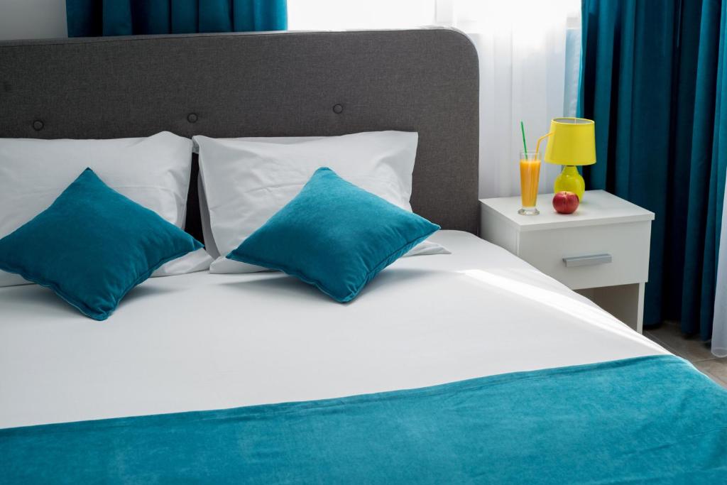 Cama blanca con almohadas azules y mesita de noche en Apartments Sunrise, en Herceg-Novi