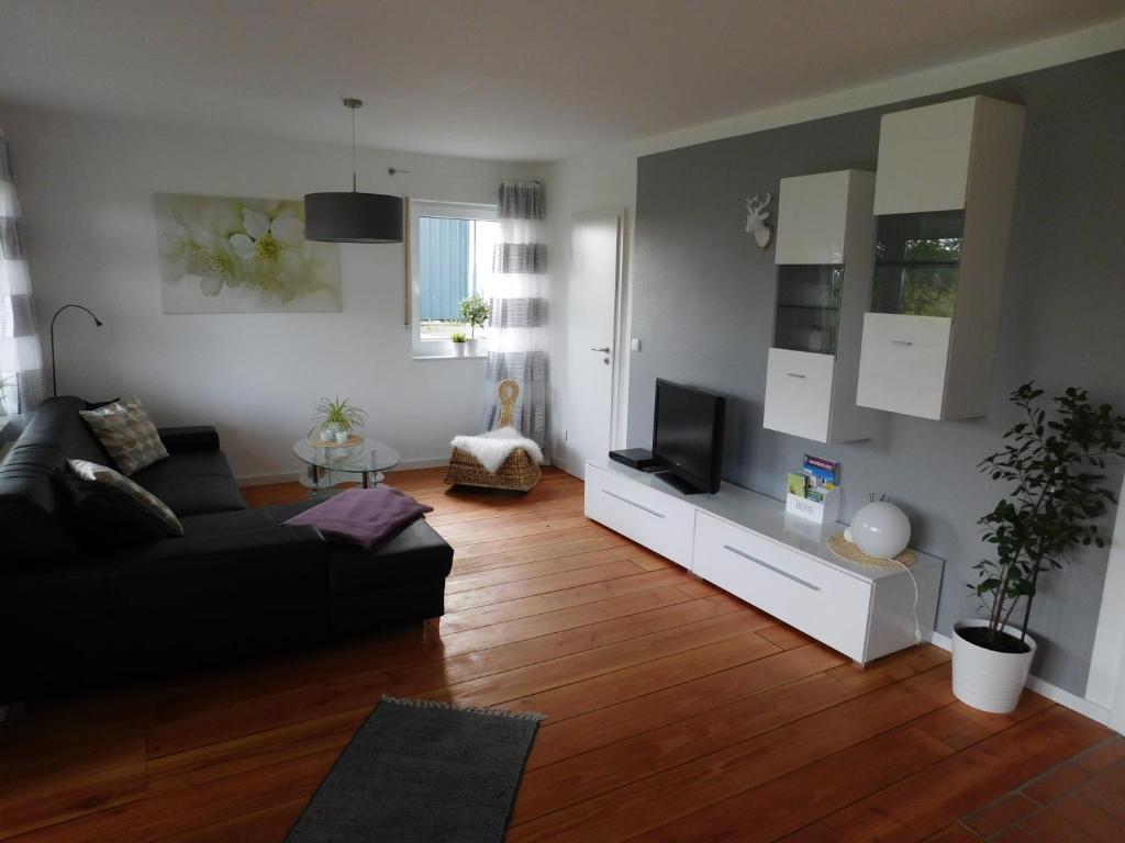 a living room with a black couch and a television at Ferienwohnung Elsbeere in Blankenheim