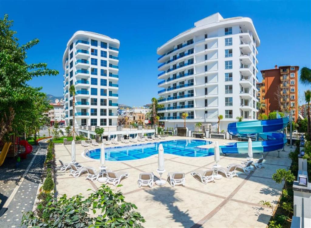 une piscine avec des chaises et deux grands bâtiments dans l'établissement Elite Marine Residence - Cleopatra, center, à Alanya