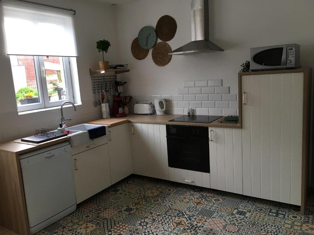 a kitchen with white cabinets and a sink and a microwave at Gîte &quot;Entre fraises et mer&quot; in Landrethun-lès-Ardres