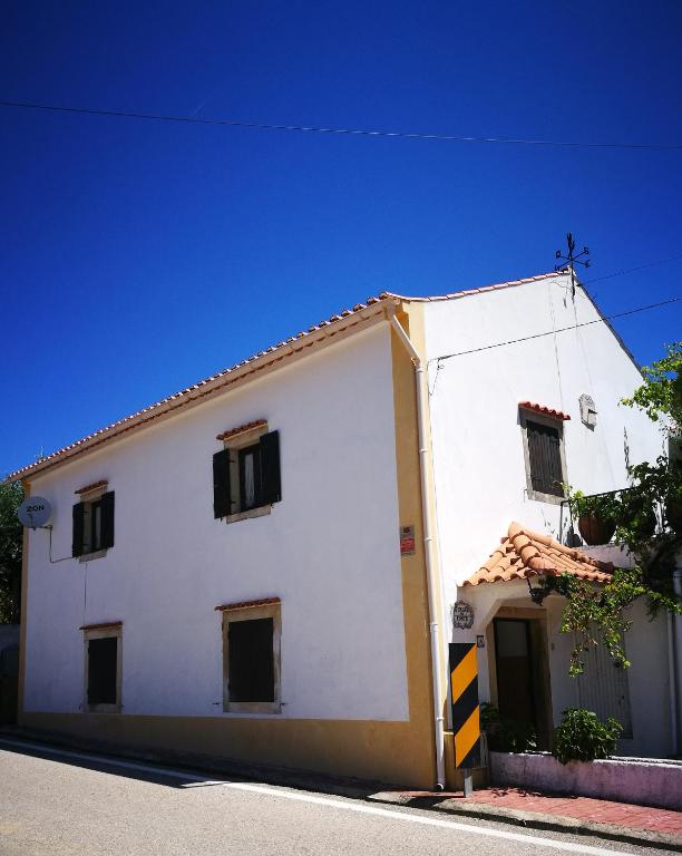 a white building with black windows on a street at A Casa da Fonte in Alviobeira