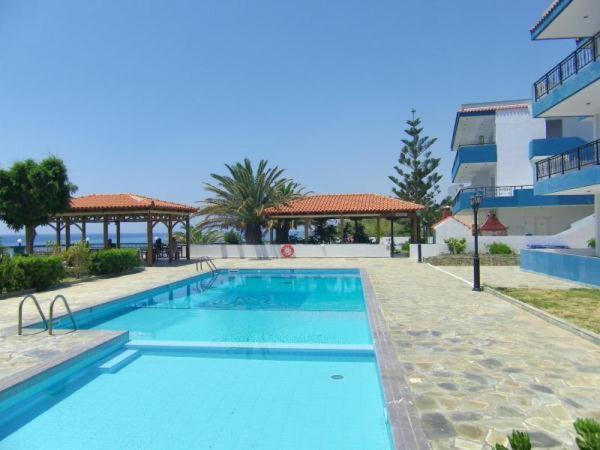 a large blue swimming pool next to a building at Cypriana Apartments in Makry Gialos