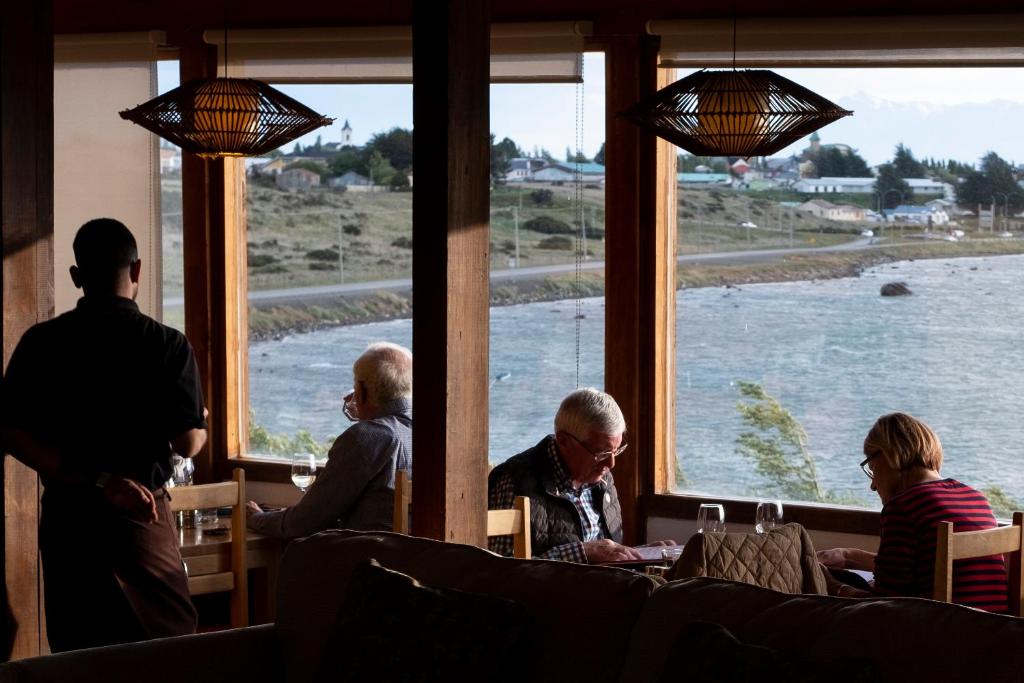 a group of people sitting at a table looking out a window at Weskar Lodge Hotel in Puerto Natales