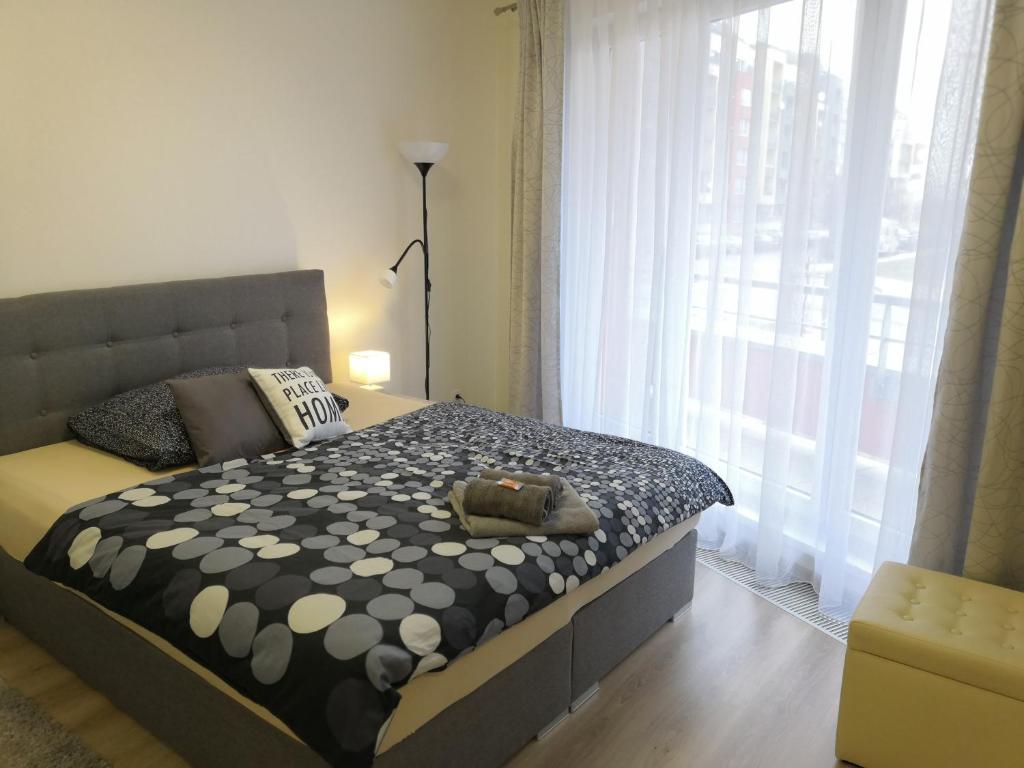 a bedroom with a bed with a large window at H+ Apartman Letiště Praha in Prague