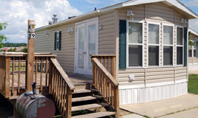 a small wooden house with a porch and a deck at Red Shoes RV Park and Chalets in Kinder
