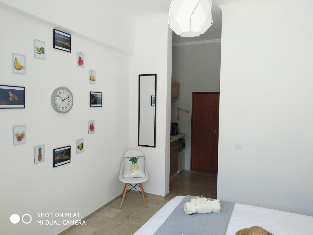 une chambre blanche avec une chaise et un réveil sur le mur dans l'établissement Studios Paleokastritsa - Sun's Gift, à Paleokastritsa