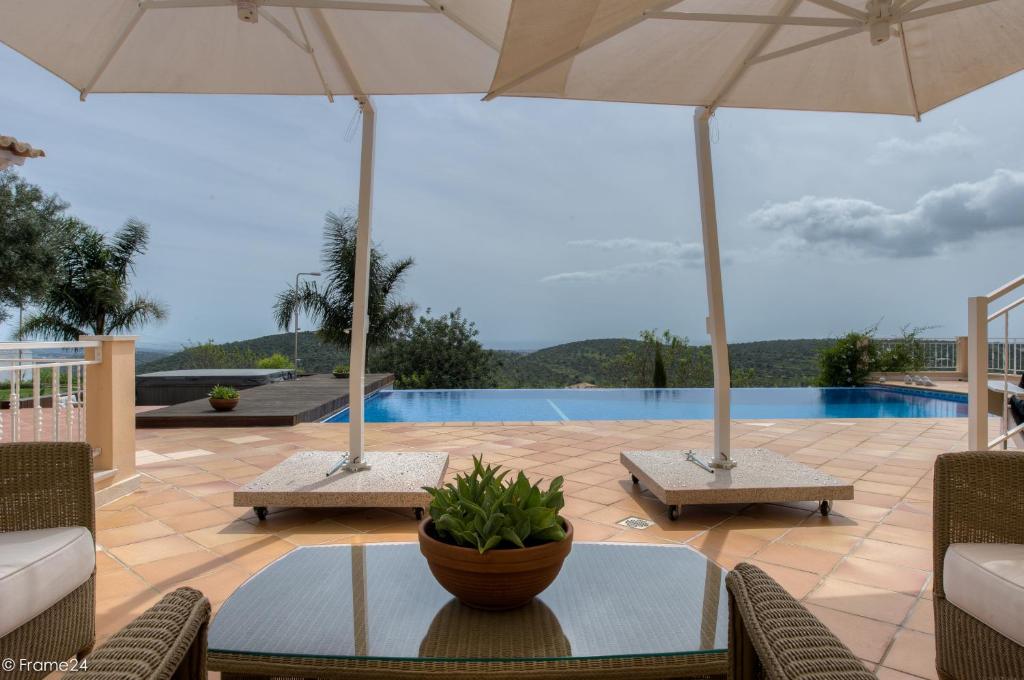 een patio met een tafel, parasols en een zwembad bij Casa Mocho Branco in Loulé