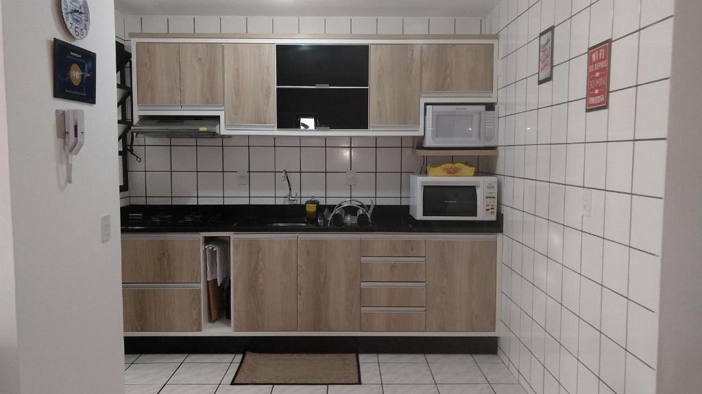 una pequeña cocina con armarios y electrodomésticos de madera en Residencial mar do norte, en Florianópolis